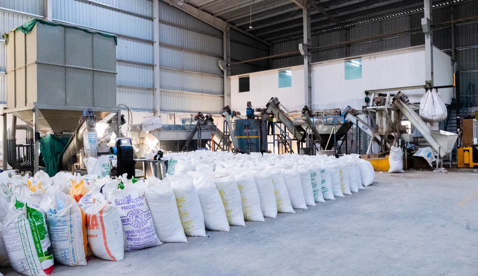 Finished output bags lined up for dispatch — full processing line running behind.