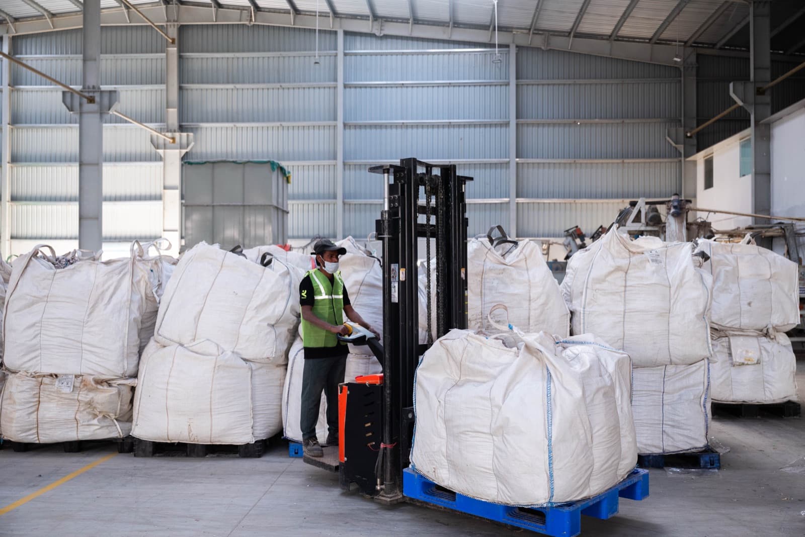 Bulk bags moved by forklift to the stacking area — each lot placed in its designated bay.