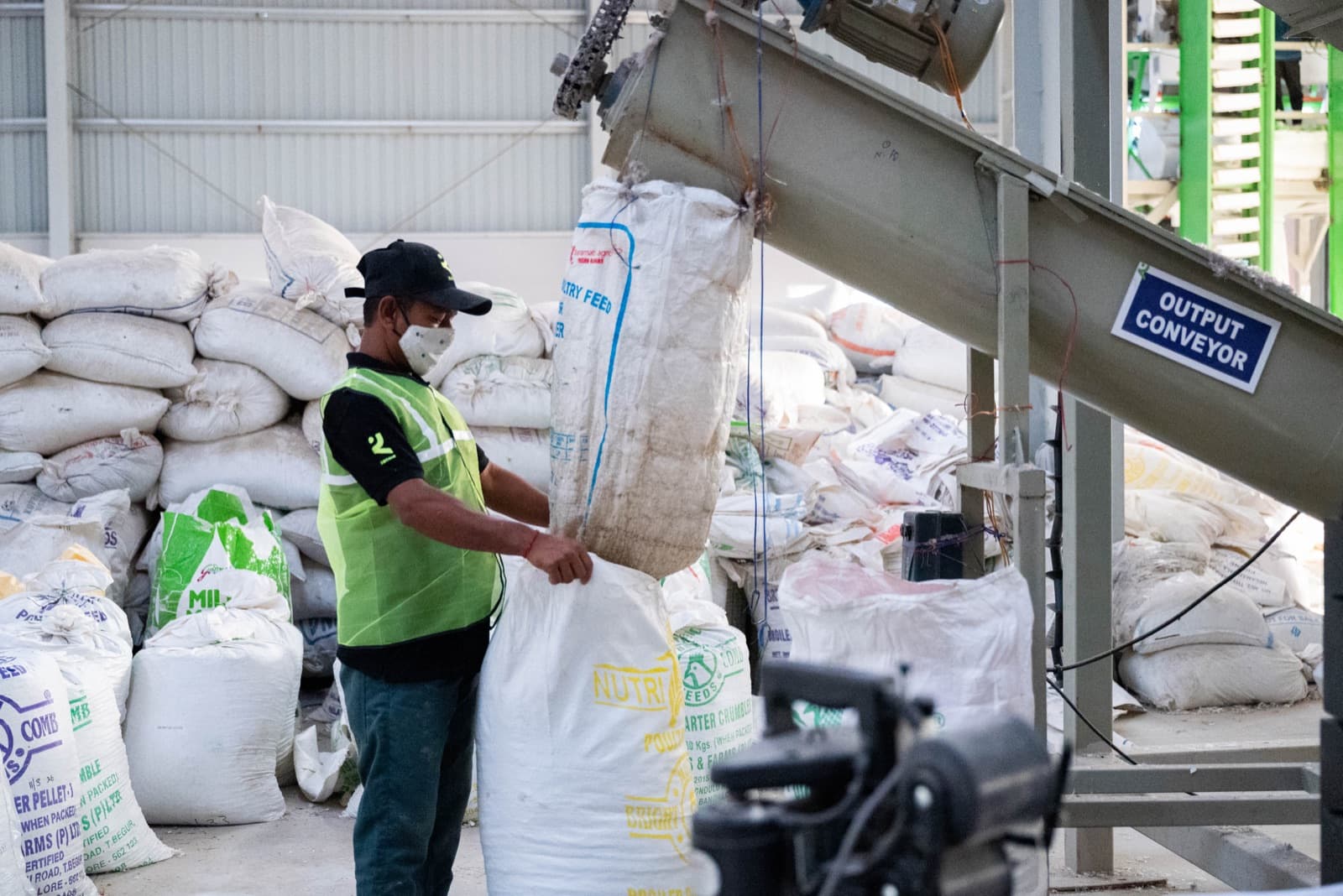 Processed material dropping off the output conveyor — bagged and weighed directly on the line.